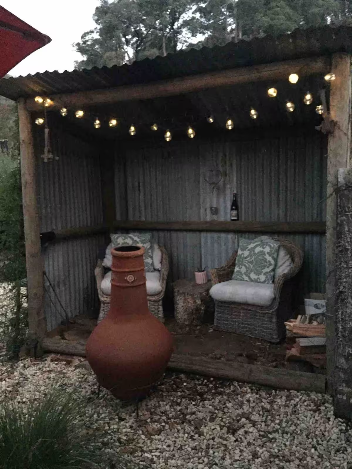 Chiminea glowing under string lights at dusk in the courtyard